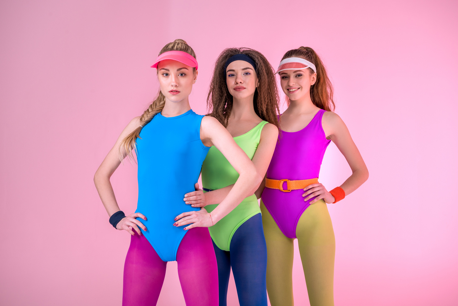 young women in fitness clothing on pink